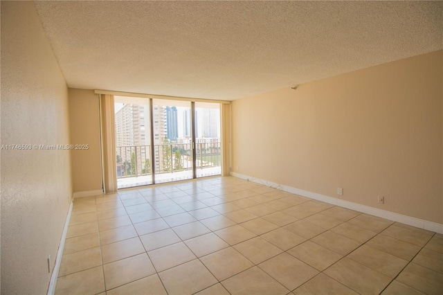 tiled spare room with expansive windows and a textured ceiling