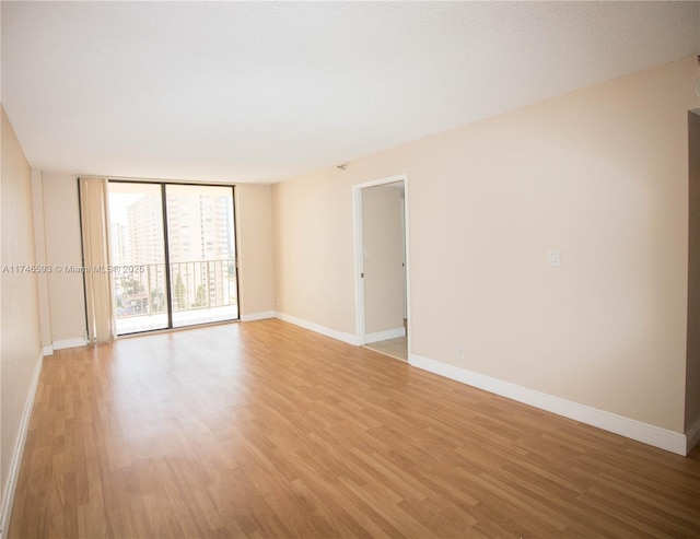 empty room featuring light wood-type flooring and floor to ceiling windows