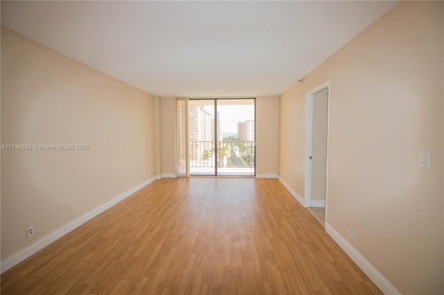 unfurnished room featuring light hardwood / wood-style floors and a wall of windows