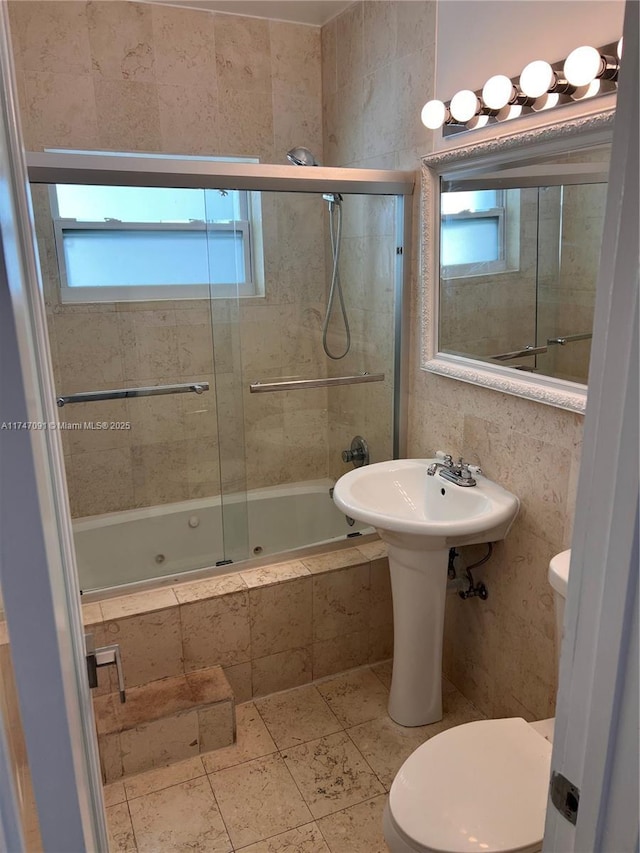 bathroom with tile patterned floors, combined bath / shower with glass door, and toilet