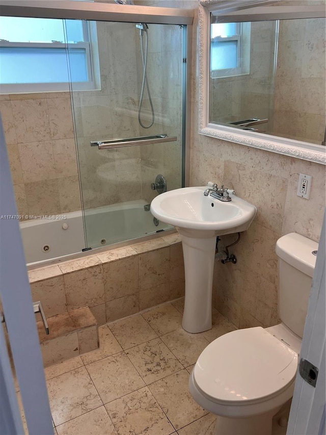 bathroom featuring combined bath / shower with glass door and toilet