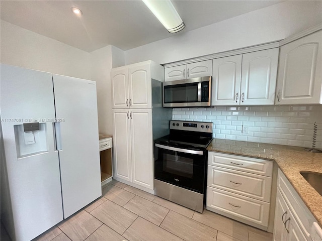 kitchen featuring appliances with stainless steel finishes, decorative backsplash, light stone counters, and white cabinets