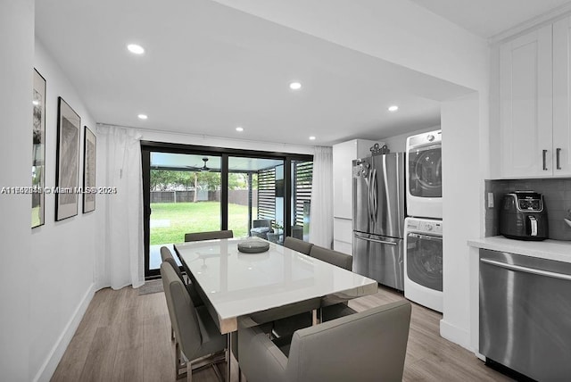 dining room featuring light wood-type flooring and stacked washer / dryer