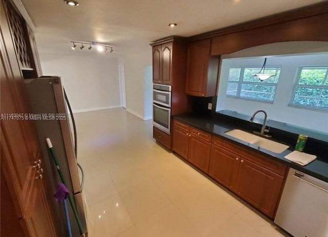 kitchen featuring dark countertops, baseboards, recessed lighting, appliances with stainless steel finishes, and a sink