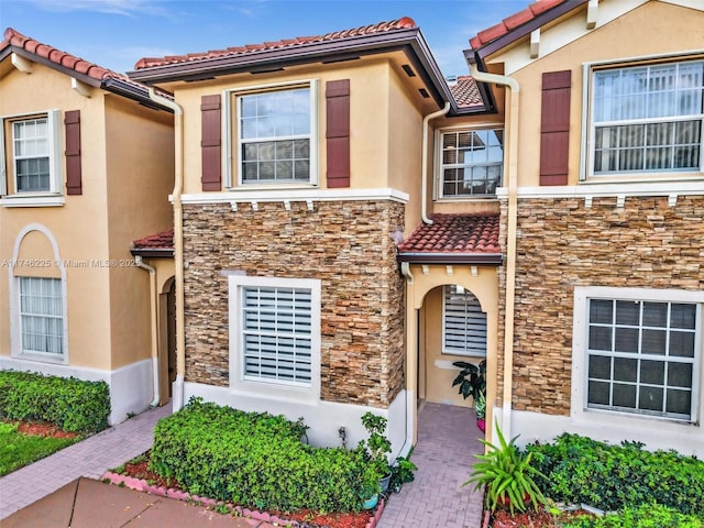 view of front of house with stone siding, a tile roof, and stucco siding