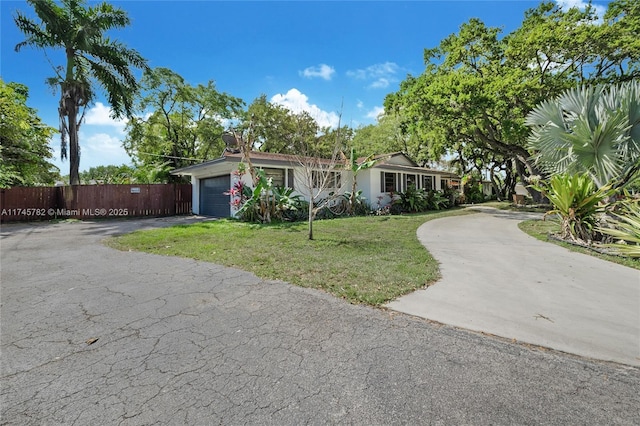 ranch-style house with driveway, an attached garage, fence, and a front yard