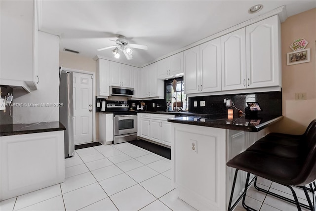 kitchen featuring stainless steel appliances, a peninsula, visible vents, white cabinets, and tasteful backsplash