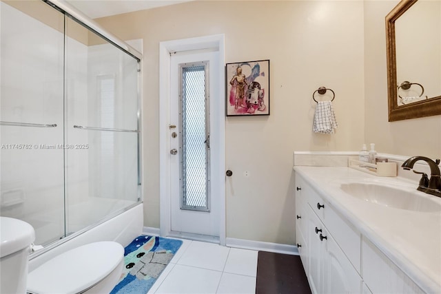 bathroom featuring baseboards, toilet, shower / bath combination with glass door, tile patterned flooring, and vanity