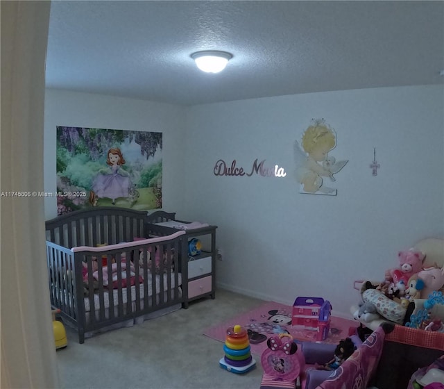 bedroom featuring a crib, carpet, and a textured ceiling