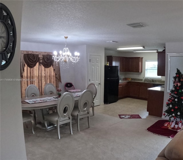 dining room with a chandelier, light carpet, a textured ceiling, and visible vents