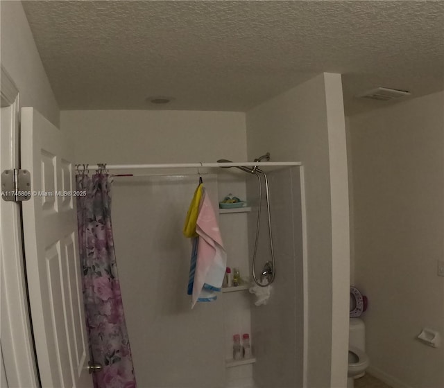 full bathroom with a textured ceiling, a shower with shower curtain, and visible vents