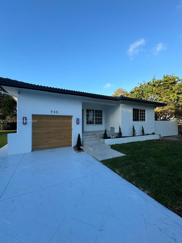 ranch-style house featuring a garage, driveway, a front yard, and stucco siding