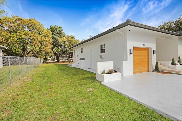 view of home's exterior with an attached garage, fence, concrete driveway, a lawn, and stucco siding