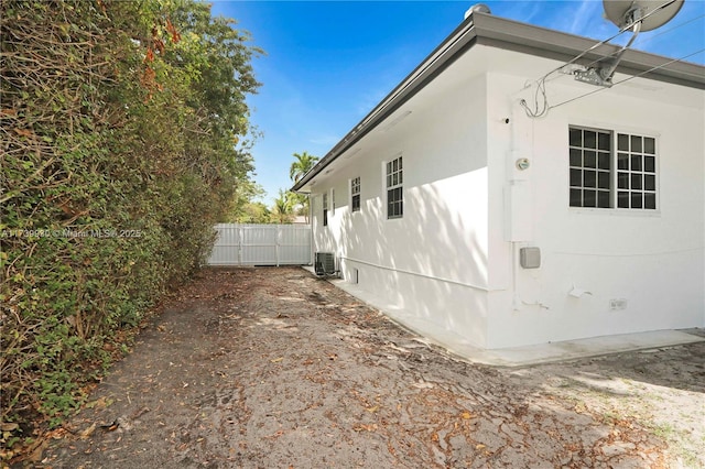 view of side of home featuring central AC and fence