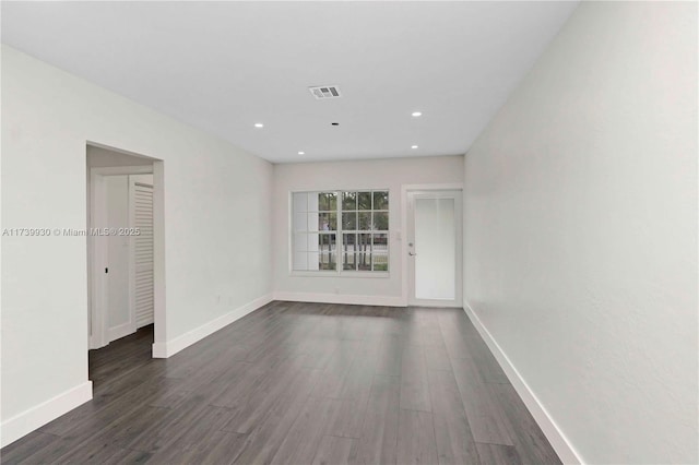 unfurnished room featuring baseboards, visible vents, dark wood finished floors, and recessed lighting