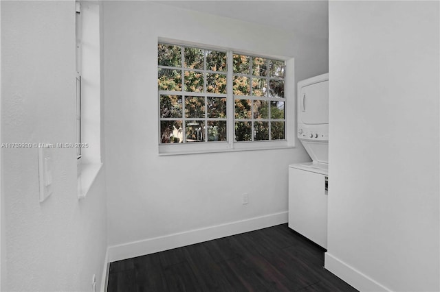 clothes washing area with stacked washer and clothes dryer, dark wood finished floors, and baseboards