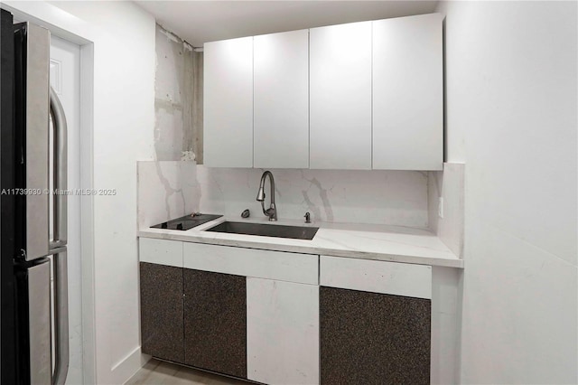 kitchen with a sink, white cabinets, freestanding refrigerator, decorative backsplash, and modern cabinets