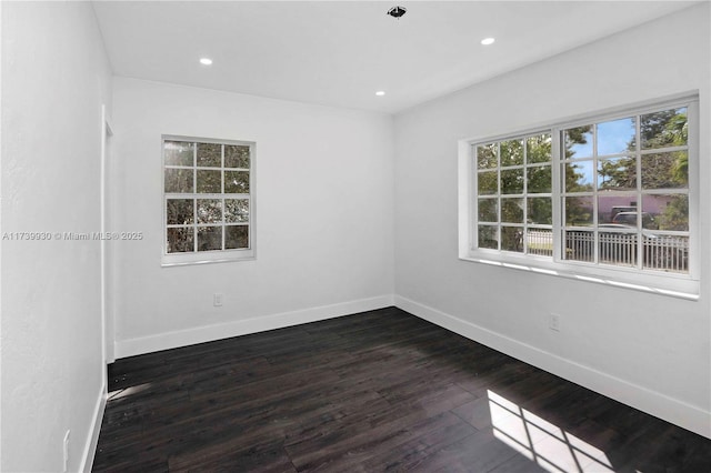 spare room with baseboards, dark wood-style flooring, and recessed lighting