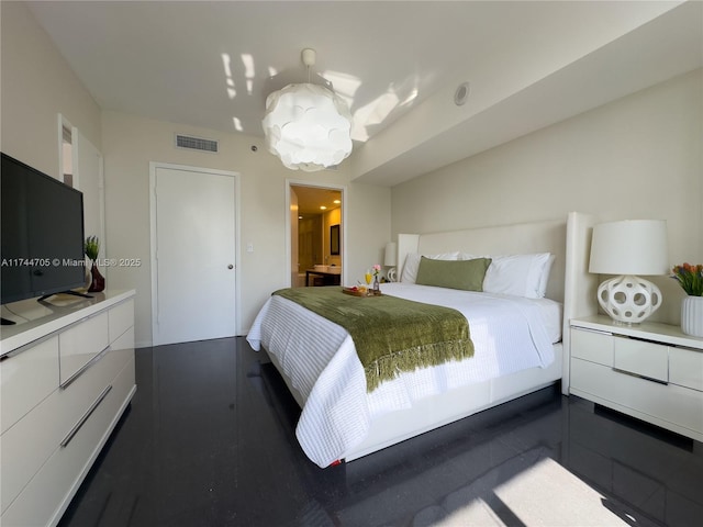 bedroom featuring dark wood-type flooring, a chandelier, and connected bathroom