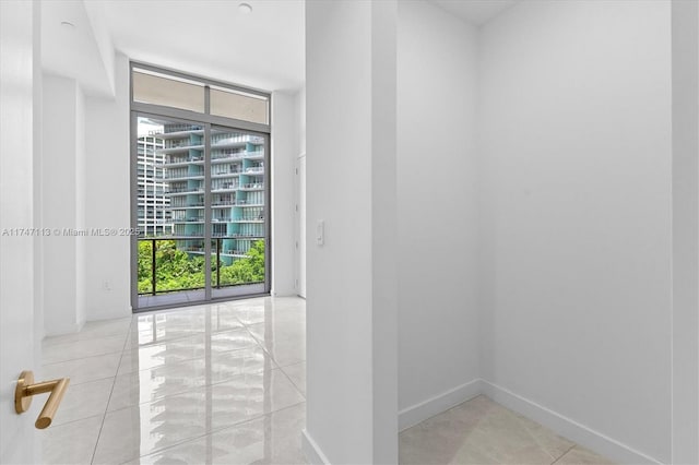 unfurnished room featuring a wall of windows and light tile patterned flooring