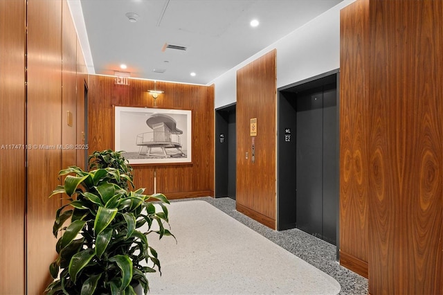 interior space featuring elevator, wood walls, and carpet floors