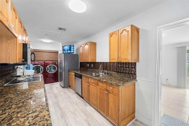 kitchen featuring decorative backsplash, visible vents, appliances with stainless steel finishes, a sink, and washer and dryer