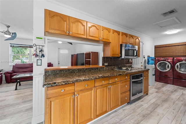 kitchen featuring stainless steel appliances, backsplash, light wood-style floors, visible vents, and washer and dryer