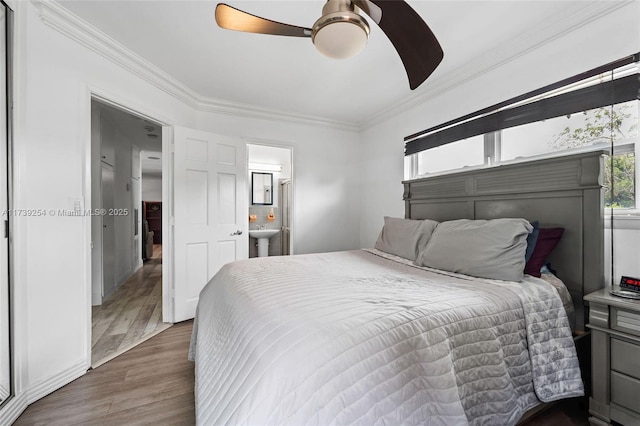 bedroom featuring multiple windows, ensuite bath, wood finished floors, and ornamental molding