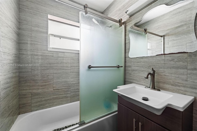 full bathroom with tile walls, bath / shower combo with glass door, and vanity