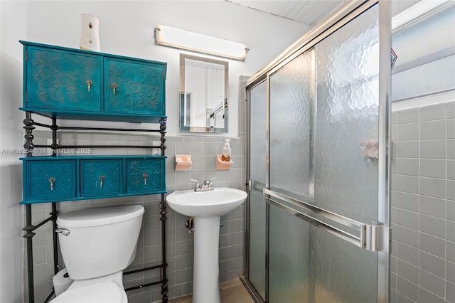 bathroom featuring tile walls, toilet, and an enclosed shower