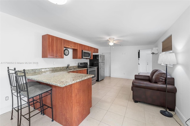 kitchen featuring stainless steel appliances, ceiling fan, a breakfast bar, light tile patterned floors, and kitchen peninsula