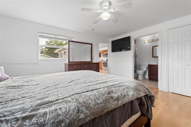 bedroom with light wood-style floors, ceiling fan, and ensuite bathroom