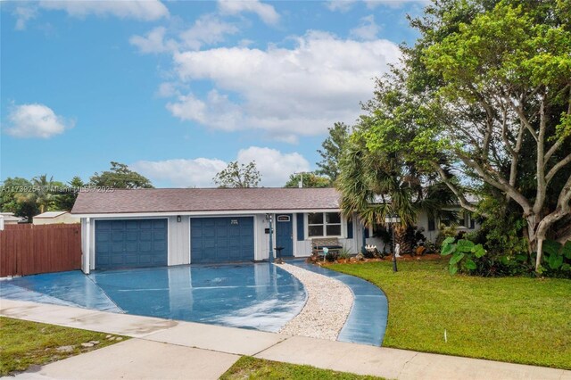 ranch-style house featuring a front yard, driveway, fence, and an attached garage