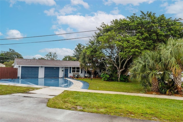 view of front of house with fence, driveway, an attached garage, and a front lawn