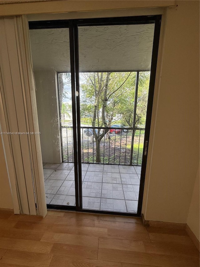 doorway to outside with light wood finished floors and baseboards