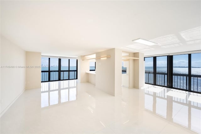 unfurnished room with a wall of windows and a water view