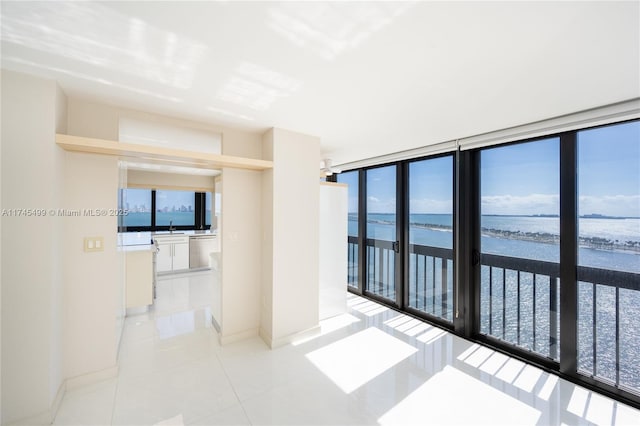 tiled spare room with a water view, sink, plenty of natural light, and floor to ceiling windows