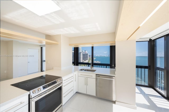 kitchen with sink, a water view, stainless steel appliances, kitchen peninsula, and white cabinets