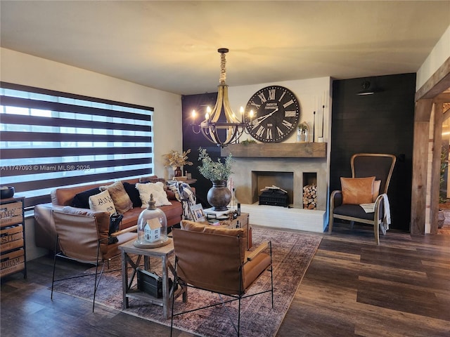 living room featuring a large fireplace, dark wood-type flooring, and a chandelier