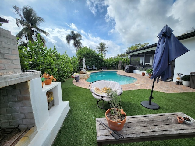 view of pool with a fireplace, a patio, a sunroom, and a yard