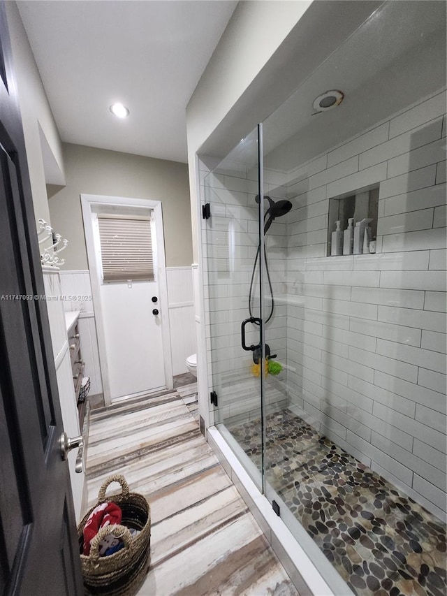 bathroom featuring hardwood / wood-style flooring, vanity, a shower with door, and toilet