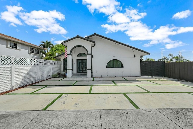 back of house featuring a tiled roof, fence, and stucco siding