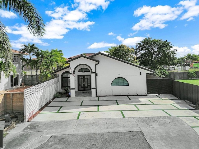 exterior space featuring a fenced front yard, french doors, a tile roof, and stucco siding