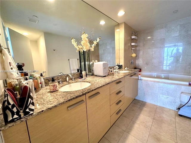 bathroom featuring tile patterned floors, vanity, and tiled tub