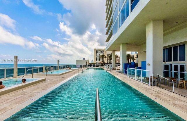 view of swimming pool with a water view and a patio area