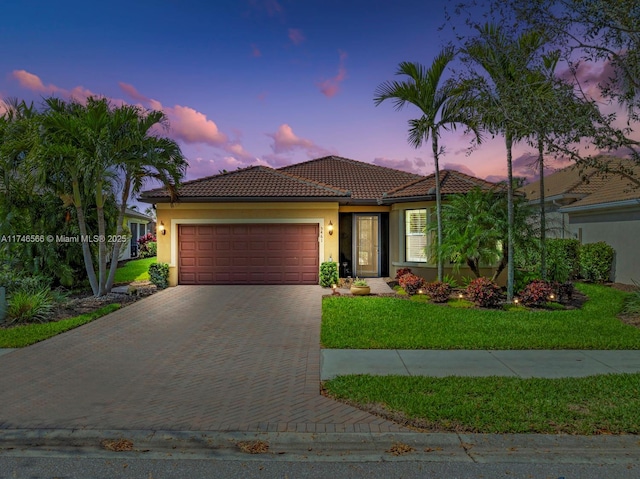 mediterranean / spanish home with a garage and a lawn