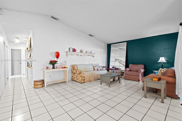 living room with a textured ceiling, lofted ceiling, and light tile patterned floors