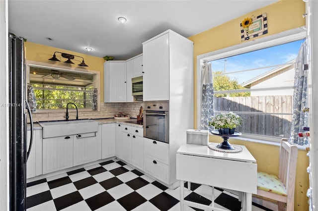 kitchen with white cabinetry, stainless steel appliances, backsplash, and sink