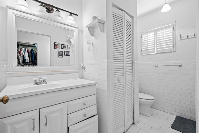 bathroom with tile walls, vanity, and toilet