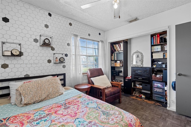 bedroom with a textured ceiling, a closet, ceiling fan, and dark parquet floors